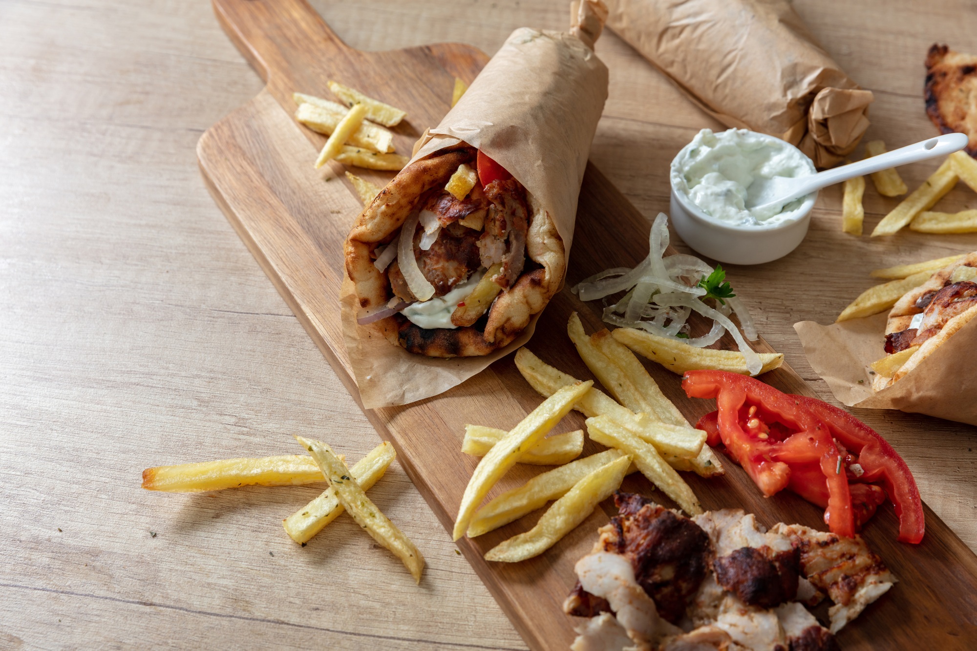 Gyro pita Shawarma wrap on wood table. Greek food with slice cut meat, overhead